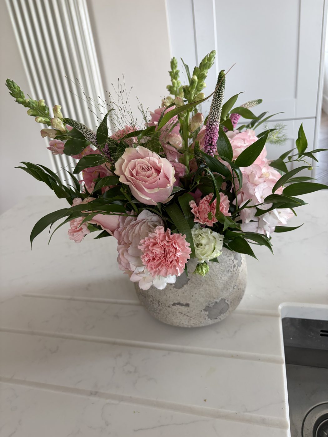 Pink rose and carnation arrangement in a stone vase