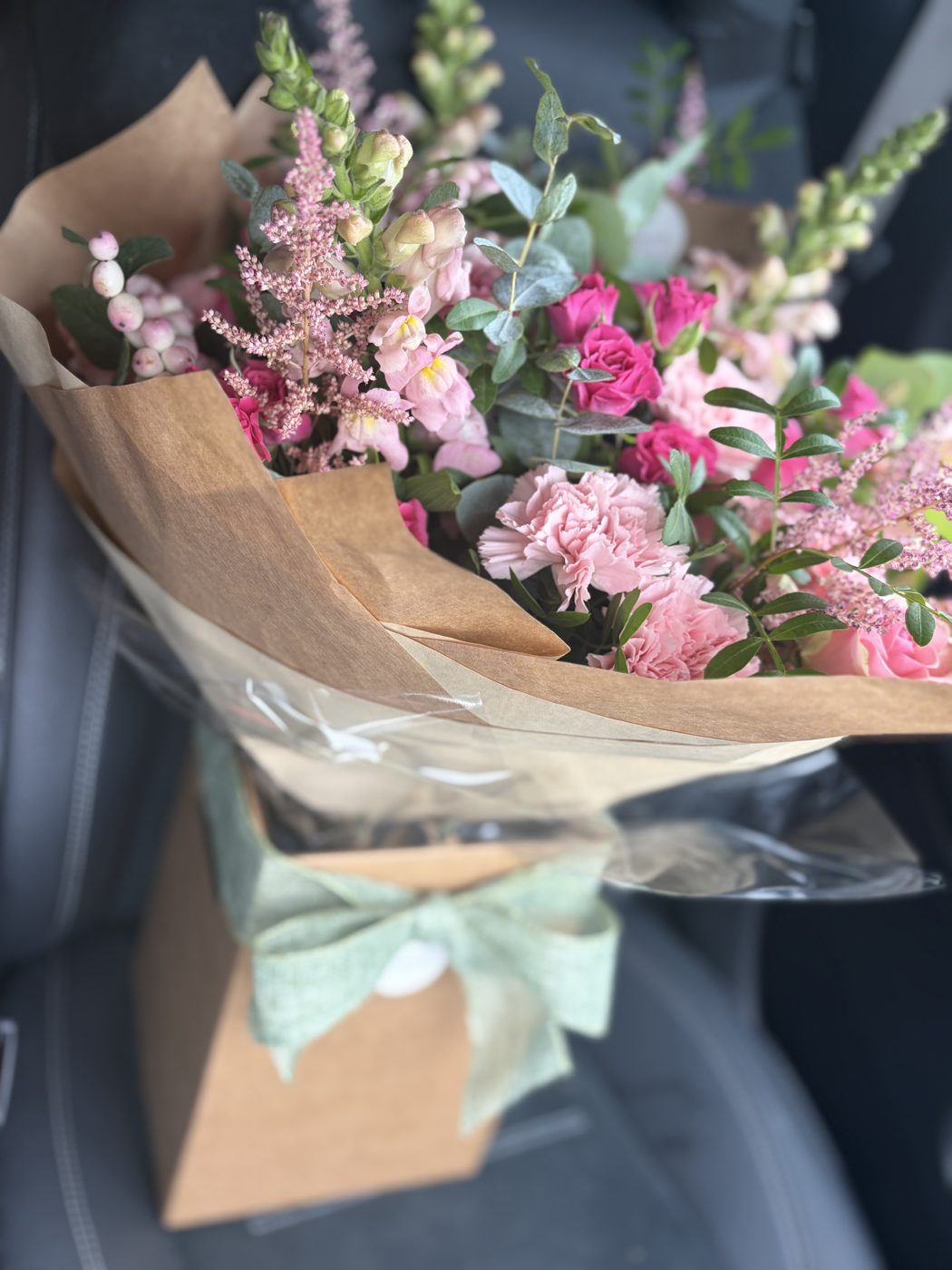 Pink astilbe, snapdragon and rose bouquet in kraft paper