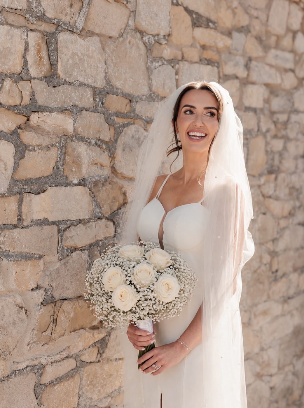 Bride holding a white rose and gypsophila bouquet